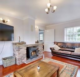 A living room with a fireplace a wall mounted television and leather sofas at Ingleside in Adsett Royal Forest of Dean