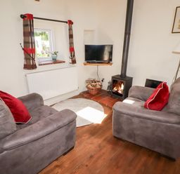 A living room with two armchairs and a wood stove at The Old Stable in Wolfscastle near Haverfordwest