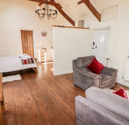 An open room with armchairs and a bed with towels on wooden floorboards at The Old Stable in Wolfscastle near Haverfordwest