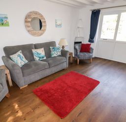 A living room with grey sofas and a red rug on wooden floor at The Duck House in Wolfscastle