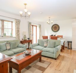 A living room with green sofas wooden tables and dining area at The Haybarn in Necton near Swaffham