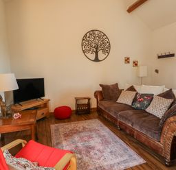 A living room with a television and sofa at Poppy Cottage in Caeathro near Caernarfon