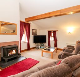 A living room with brown sofas a fireplace a television and wooden beams at The Dairy in Milton near Brampton
