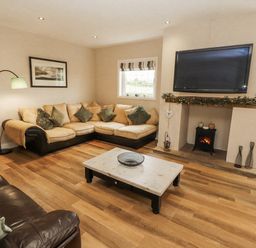 A living room with a TV and sofa at White Gables in Great Clifton near Cockermouth