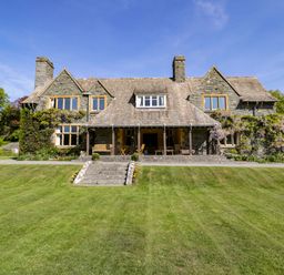 Stone house with two chimneys and a large lawn in front at Plas Gwynfryn in Llanbedr