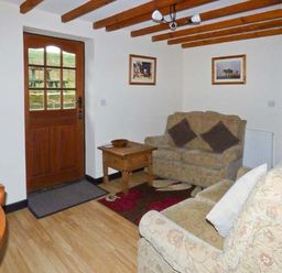 A living room with two sofas a wooden door a wooden coffee table and framed pictures on the walls at The Stable in Aislaby near Whitby
