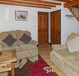 A sitting room with two sofas a wooden table a rug and wooden doors at The Stable in Aislaby near Whitby