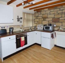 A kitchen with white cabinets wooden countertop microwave oven toaster and kettle at The Stable in Aislaby near Whitby