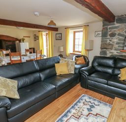 A living room with sofas and a dining area at Daffodil Cottage in Caeathro near Caernarfon