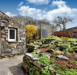 A stone wall house with a garden and outdoor wooden table and chairs at Ty Capel Jeriwsalem in Bronaber near Trawsfynydd