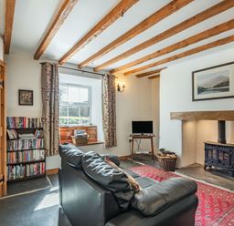 A sitting room with leather sofas a wood stove and a bookshelf at Ty Capel Jeriwsalem in Bronaber near Trawsfynydd