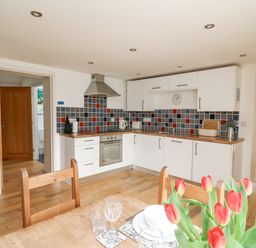 A kitchen with white cabinets and colorful tiled backsplash at Y Cwtch in Newport