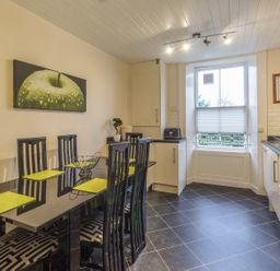 A kitchen with a black dining table and six chairs a window countertop appliances and cabinets at The Old Exchange in Corbridge near Hexham