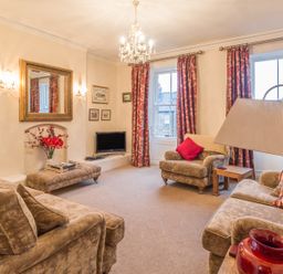 A living room with beige sofas red curtains and a chandelier at The Old Exchange Corbridge near Hexham