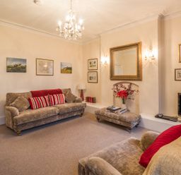 A living room with sofas cushions a chandelier wall art mirror and a television at The Old Exchange in Corbridge near Hexham