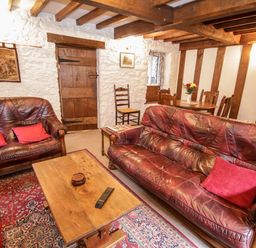 A living room with two leather sofas a wooden coffee table and dining table at Nant Cottage in Llanrwst near Betws-y-Coed