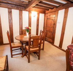 A room with a round wooden table with four chairs and a vase of flowers on the table at Nant Cottage in Llanrwst near Betws-y-Coed