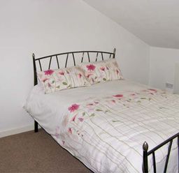 A bedroom with a bed featuring floral bedding and pillows at Hendre Aled Cottage 3 in Llansannan