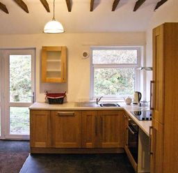 A kitchen with wooden cabinets a door and a window at Hendre Aled Cottage 1 in Llansannan near Llanrwst