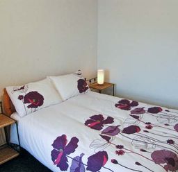 A bedroom with a double bed with floral bedding and two bedside tables with lamps at Hendre Aled Cottage 1 Llansannan near Llanrwst