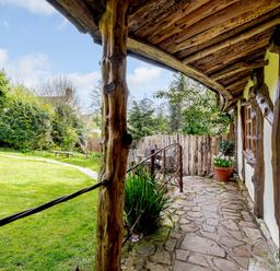 A stone path alongside a rustic timber house with wooden beams and a covered porch at Brookbank Folly in Mitcheldean