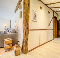 A living room with a gray sofa wooden side tables floor lamps and wooden beams on the walls at Brookbank Folly in Mitcheldean