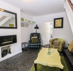 A living room with a yellow coffee table and green chair at Hollie Cottage in Haltwhistle