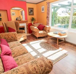 A living room with patterned sofa and armchairs a coffee table and a large window at Cra-na-ge in Embleton