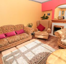 A living room with patterned sofas an armchair a rug a wooden coffee table a fireplace and a mirror at Cra-na-ge in Embleton