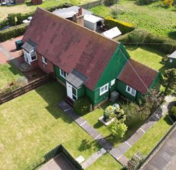 An aerial view of a green and brick house with a tiled roof surrounded by grass and garden sheds at Cra-na-ge Embleton