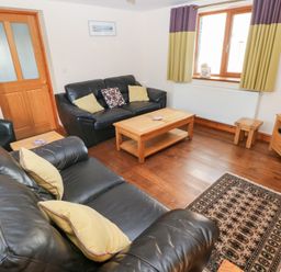 A living room with a sofa and coffee table at Bwthyn Trecoed St. Clears near Carmarthen