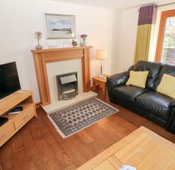 A living room with a sofa and television at Bwthyn Trecoed in St. Clears near Carmarthen