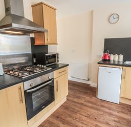 A kitchen with a stove oven toaster microwave red kettle and sink at No 1 Low Hall Cottages Scalby near Scarborough