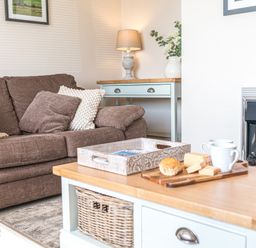 A living room with a brown sofa cushions lamp vase and fireplace at Colt Park Cottage in Ulverston