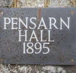 A metal plaque on a stone wall with the text Pensarn Hall 1895 at Pensarn Hall in Llanbedr near Harlech