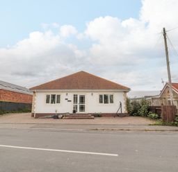 A single story house with red tiled roof and white walls facing a street at On The Watersedge in Beadnell