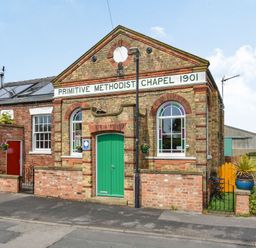 Front view of a brick chapel with green door and arched windows with stained glass at The New Chapel in Great Hatfield near Hornsea