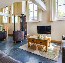 A living room with leather sofas a coffee table with tea set and a dining area with wooden table and chairs at The New Chapel Great Hatfield near Hornsea