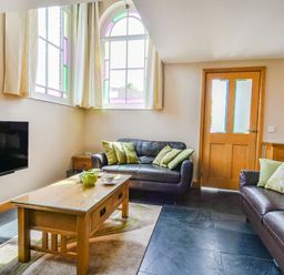 A living room with two leather sofas a wooden coffee table and a TV on the wall at The New Chapel in Great Hatfield near Hornsea