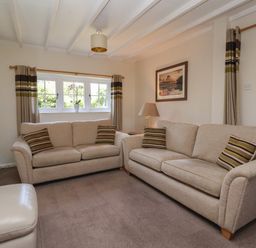 A sitting room with two beige sofas with striped cushions a small lamp and framed picture at Waggoner's Cottage in Bessingby near Bridlington