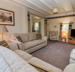 A living room with sofas armchair television and lamps at Waggoner's Cottage in Bessingby near Bridlington