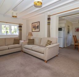 A living room with two beige sofas and striped cushions next to a dining area with wooden chairs at Waggoner's Cottage in Bessingby near Bridlington