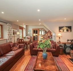 A living room with a sofa, table, and chairs at The Lodge Farm Barn Deepdean near Ross-on-Wye