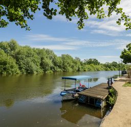 A river with a boat at a dock surrounded by trees at Severn Bank Lodge Astley Burf near Stourport-on-Severn