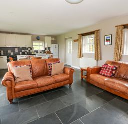 A living room with sofa and kitchen in the background at Blaenffynnon Bach in Trelech near Crymych