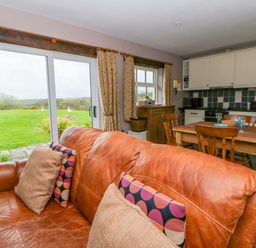 A living room with a sofa and dining area at Blaenffynnon Bach in Trelech near Crymych