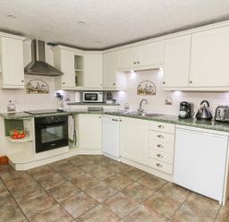 A kitchen with white cabinets appliances microwave toaster and kettle at Tangaer Cottage in Cellan near Lampeter