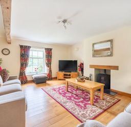 A living room with sofas coffee table television fireplace and window at Old Rectory Cottages Aberhafesp near Newtown