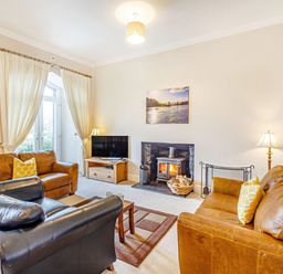 A living room with leather sofas a television and a wood burning stove at Menai View in Llanfairpwllgwyngyll near Beaumaris