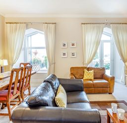 A living room with two sofas a wooden dining table with chairs and a television at Menai View in Llanfairpwllgwyngyll near Beaumaris